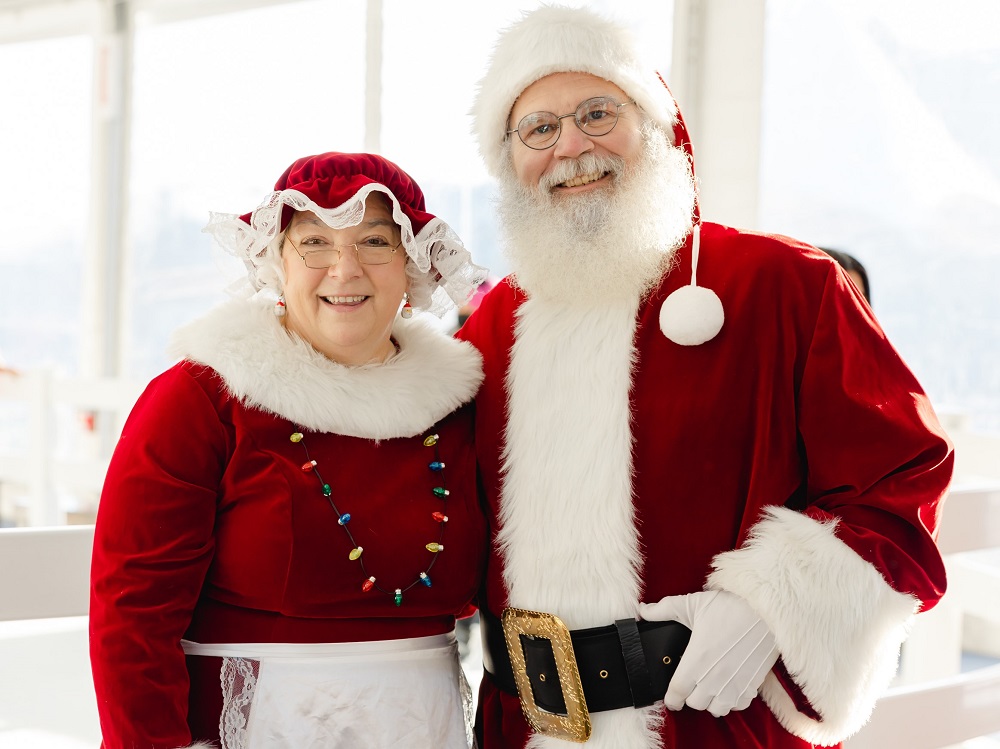 Mr. & Mrs. Claus standing arm in arm with beautiful holiday smiles.